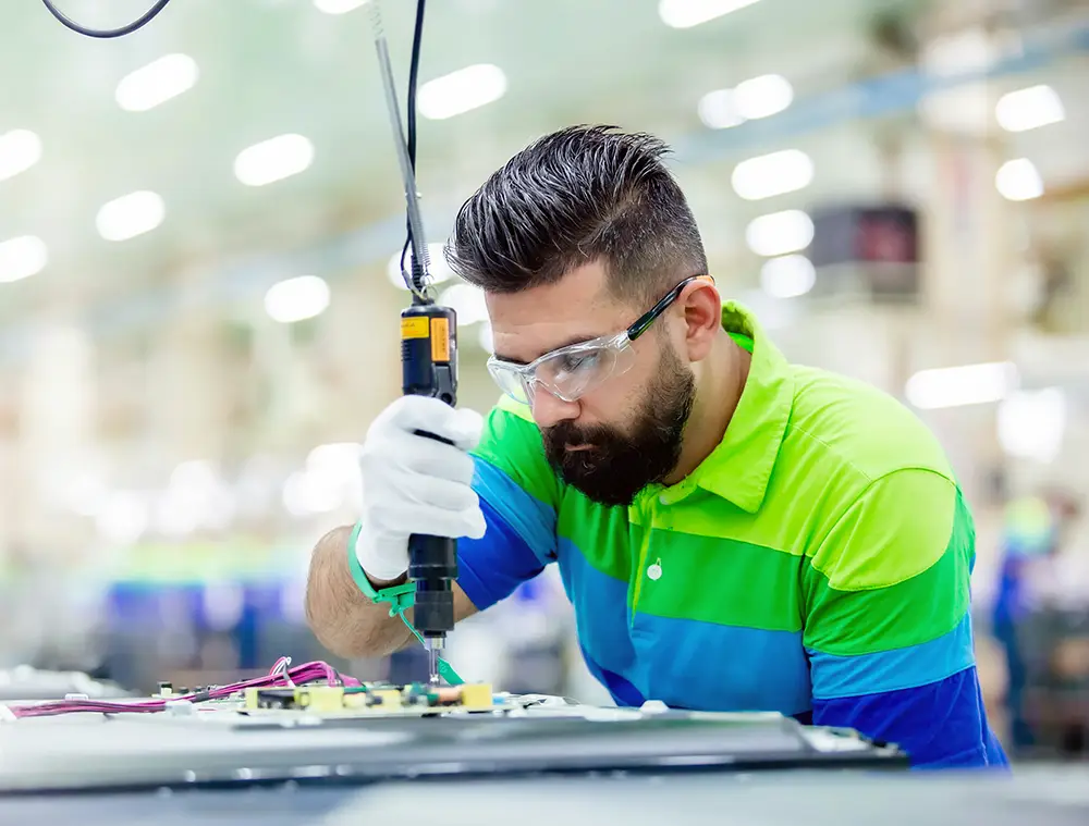 it-managed-services-manufacturing-worker-tech-support Technician assembling electronics on a manufacturing production line with precision tools