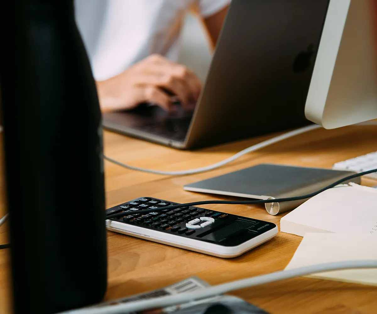 managed-it-financial-analyst-desk Managed IT for financial industry with analyst using desktop and calculator in modern office