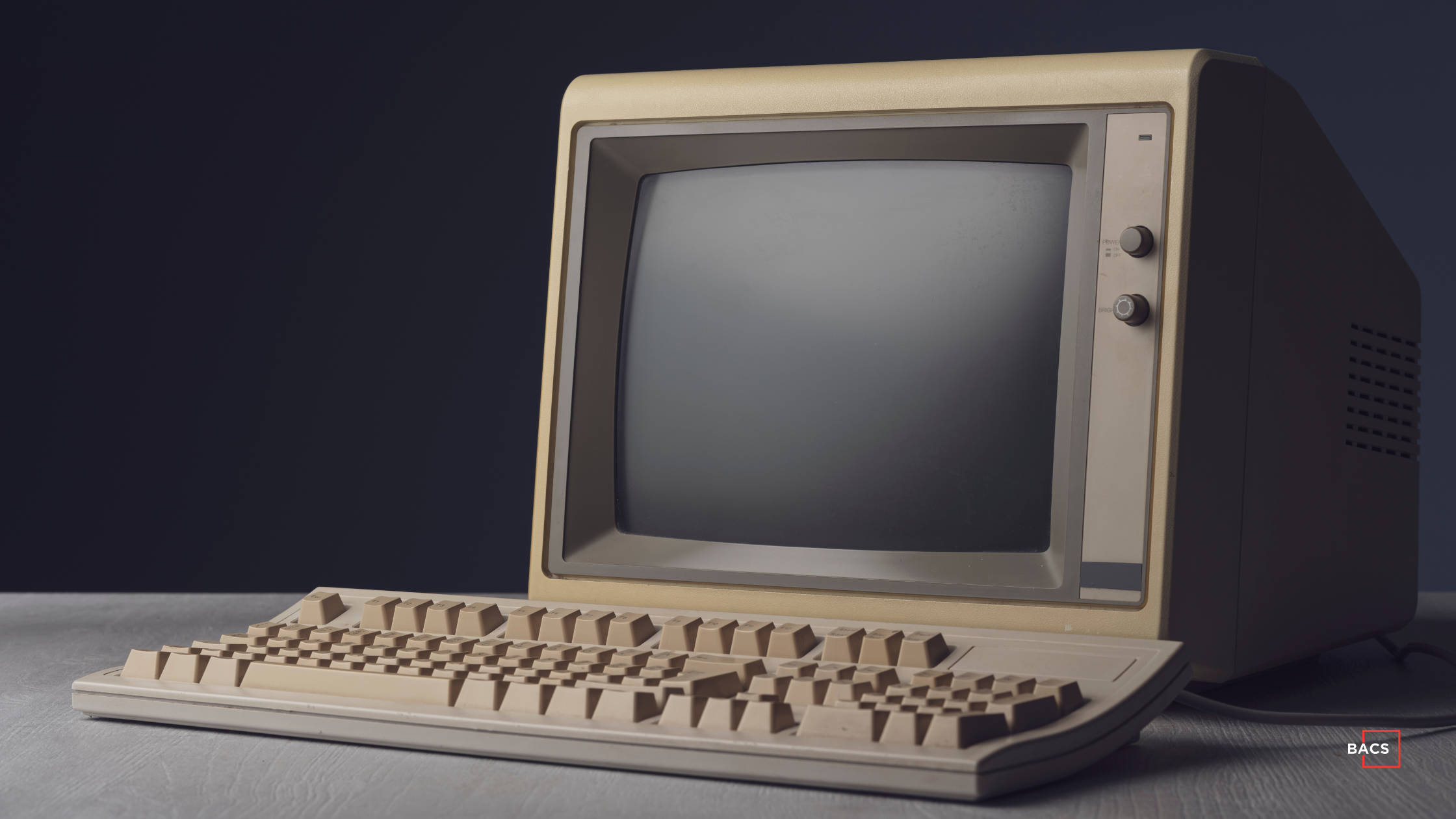 Retro 1980s vintage computer with CRT monitor and beige keyboard, classic antique desktop technology for collectors or IT history blogs, with BACS branding.