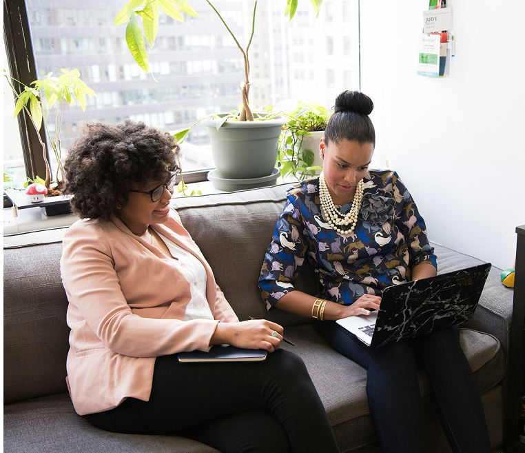 businesswomen-collaborating-small-office-laptop Two businesswomen reviewing work on a laptop in a small office setting