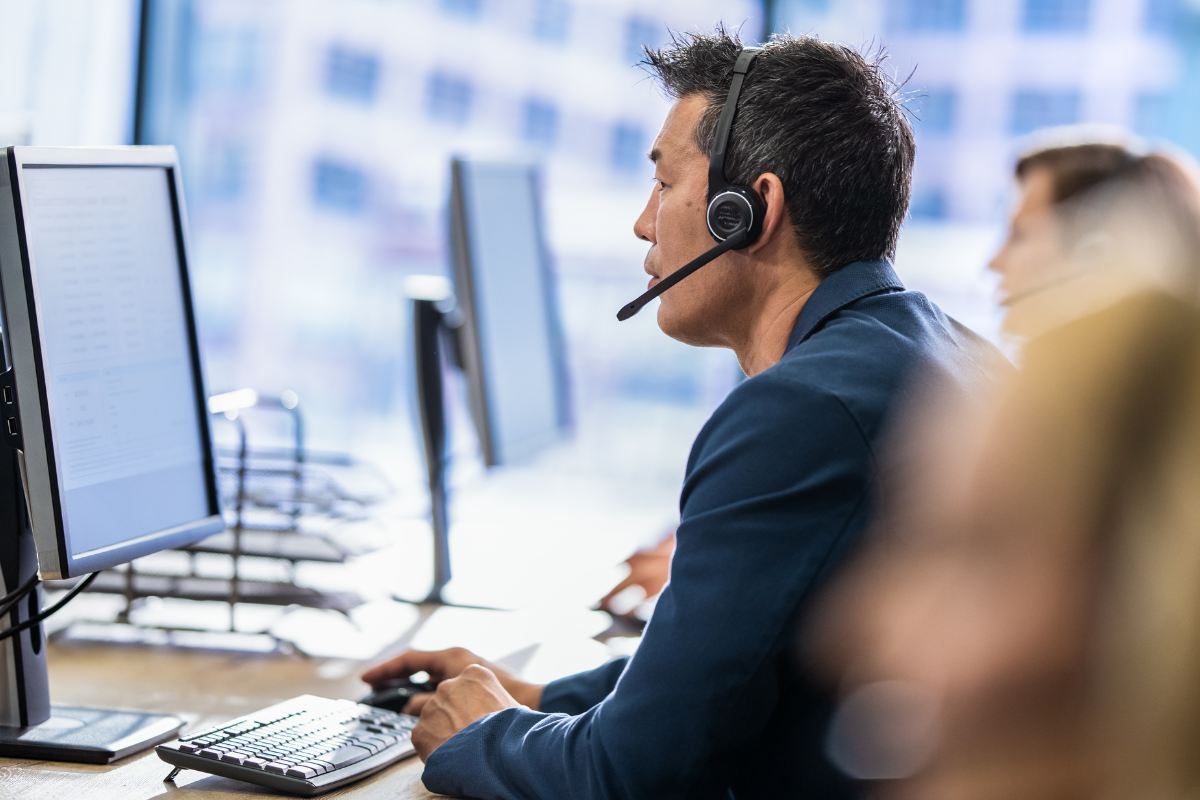 Microsoft Copilot training support showing an employee using technology at a workstation with headset assistance